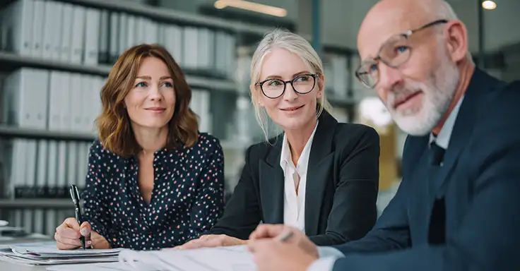 Drei Personen im Gespräch über Immobilienverkauf